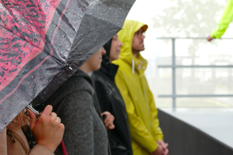 Publikum im regen mit Regenschirm